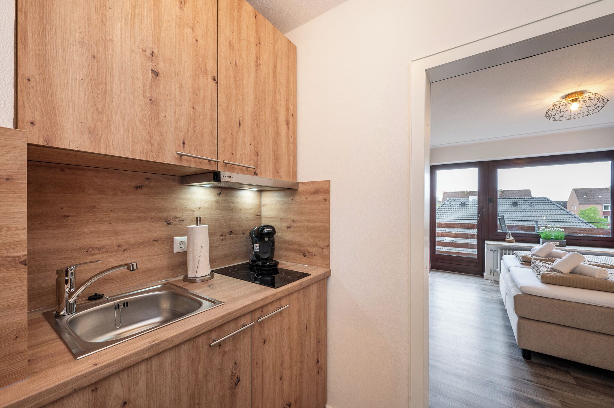 Une cuisine moderne avec des meubles en bois, un évier en acier inoxydable et une machine à café.