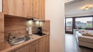 A modern kitchen with wooden cabinets, a stainless steel sink, and a coffee maker. - Quartier 16<br>Apartment in a quiet location and access to sea time (Büsum)