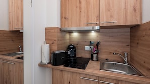 A compact kitchen with wooden cabinets, a toaster, a coffee maker, and a sink.