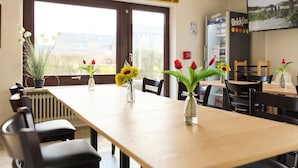 A dining area with a long table, chairs, and vases with flowers.