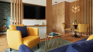 A modern living room with a yellow sofa, a large flat-screen TV, a round coffee table, and a wooden accent wall. - First class apartment with covered terrace close to the beach! (Sankt Peter-Ording)