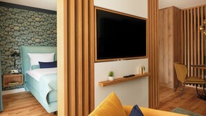A modern bedroom with a bed, a TV mounted on the wall, a bedside table, and a small shelf with decorative items. - First class apartment with covered terrace close to the beach! (Sankt Peter-Ording)