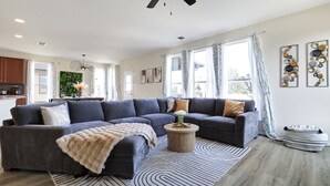 Ein modernes Wohnzimmer mit einem Ecksofa, einem runden Couchtisch und einem gemusterten Teppich.
