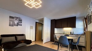 A compact living space with a sofa, a dining table with chairs, a kitchenette, and a ceiling light fixture. - cosy 26 sqm studio is located in the Swiss Alps ski resort of Les Collons (Vex (Les Collons))