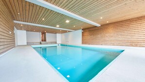 An indoor swimming pool with a wooden ceiling and walls, a clear blue pool, and a visible door in the background. - Cosy studio for 5 near ski lift, HAMEAU C13 (Les Collons (Vex))