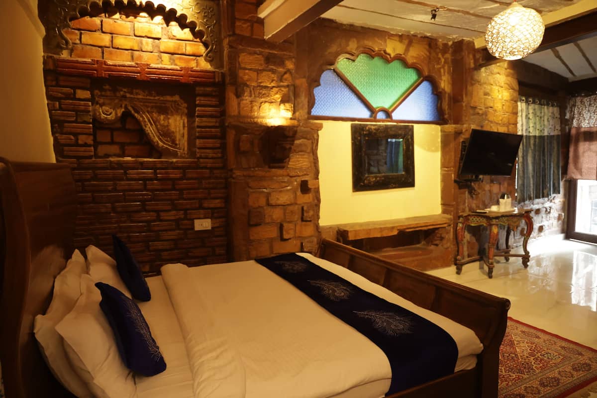 A bedroom with a brick fireplace, a bed with white and blue bedding, a television on a wooden stand, and a patterned rug on the floor.