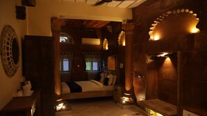A cozy room with a bed, wooden furniture, and a fireplace. - Jhankar Haveli (Jodhpur)