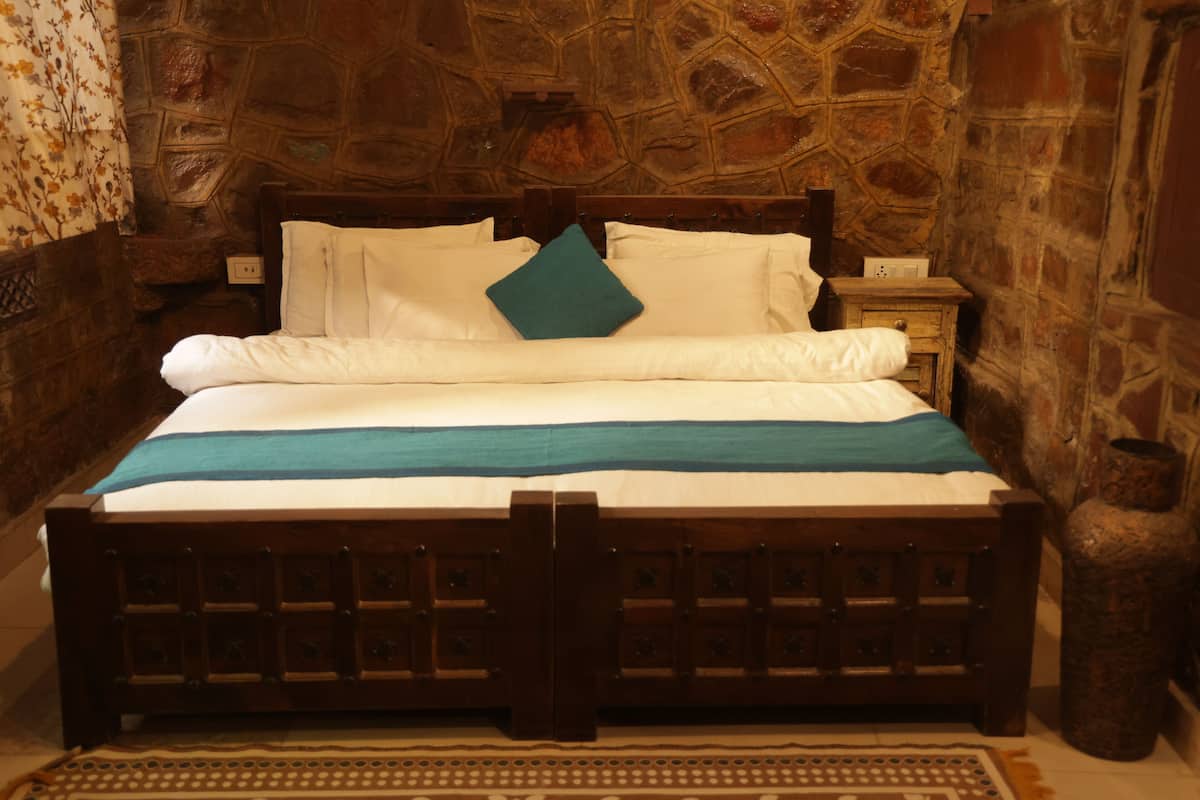 A bed with a wooden frame, white bedding, and a teal pillow.