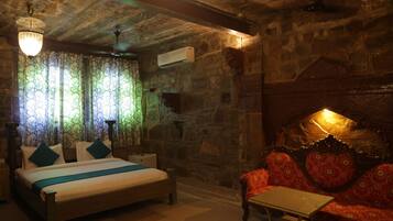 Una habitación con una cama, un sofá, una mesa y una pared de piedra.
