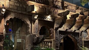 An intricately carved stone structure with arches and columns, potted plants, and a sign reading "HANKAR HAVELI". - Jhankar Haveli (Jodhpur)