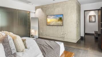 Ein modernes Schlafzimmer mit einem großen Bett, einer Wand aus Beton, einem Gemälde und einer hölzernen Bank.