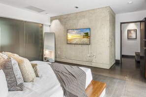 Ein modernes Schlafzimmer mit einem großen Bett, einer Wand aus Beton, einem Gemälde und einer hölzernen Bank.