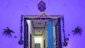 A hallway with a decorative archway, a blue pillar, and a patterned floor. - Yash Paying Guest House (Varanasi)