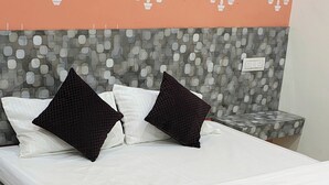 A bed with white bedding and two black pillows, a marble-patterned floor, and a wall with a polka dot and sailboat design. - Yash Paying Guest House (Varanasi)