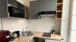 Une cuisine compacte équipée d’un lave-linge, d’un four à micro-ondes, d’un petit réfrigérateur et d’un évier.