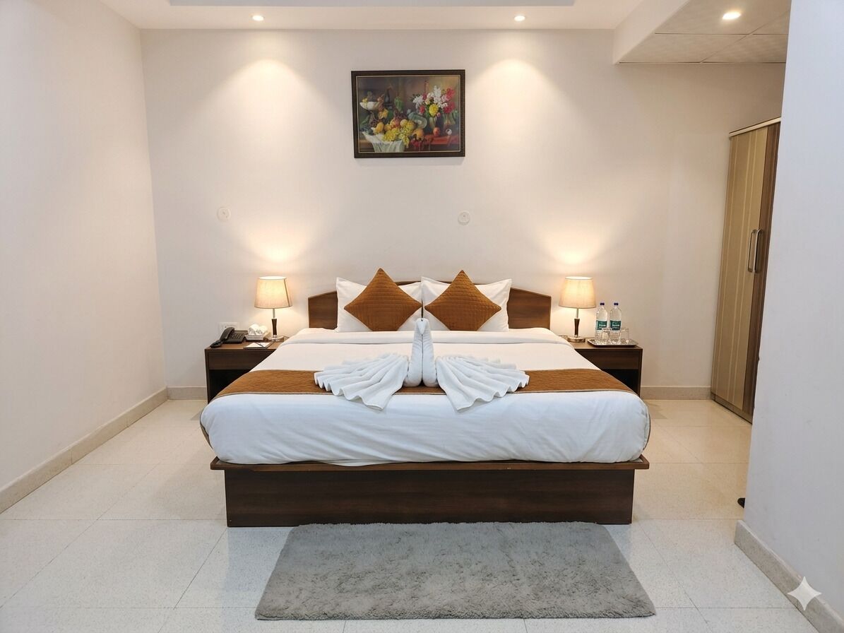 Une chambre d’hôtel avec un lit, deux tables de chevet, une petite table, une armoire en bois et un tableau au mur.