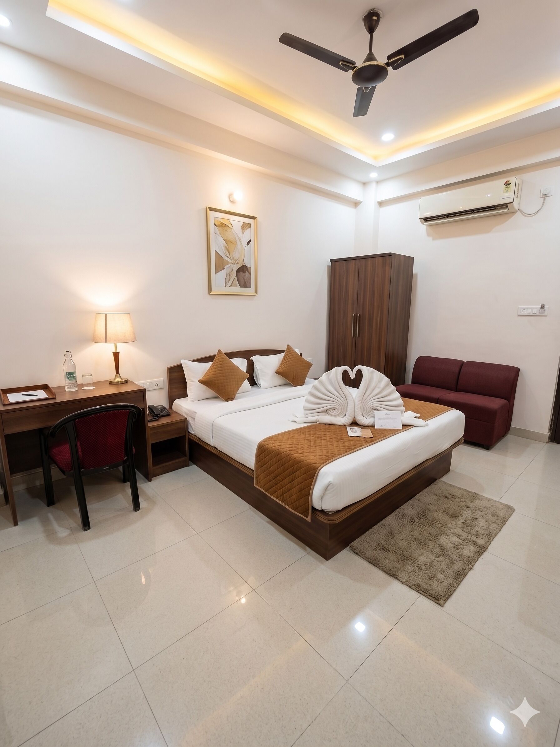 A hotel room with a bed, desk, chair, wardrobe, and a red sofa.