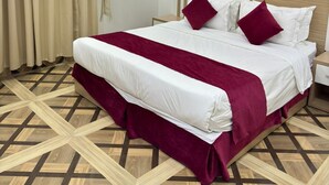 Een moderne hotelkamer met een groot bed, een marmeren wand en een vloer met een geometrisch patroon.
