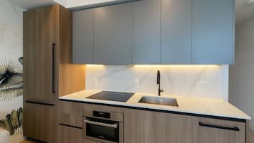 Una cocina moderna con armarios de madera, encimera negra, horno empotrado y fregadero.