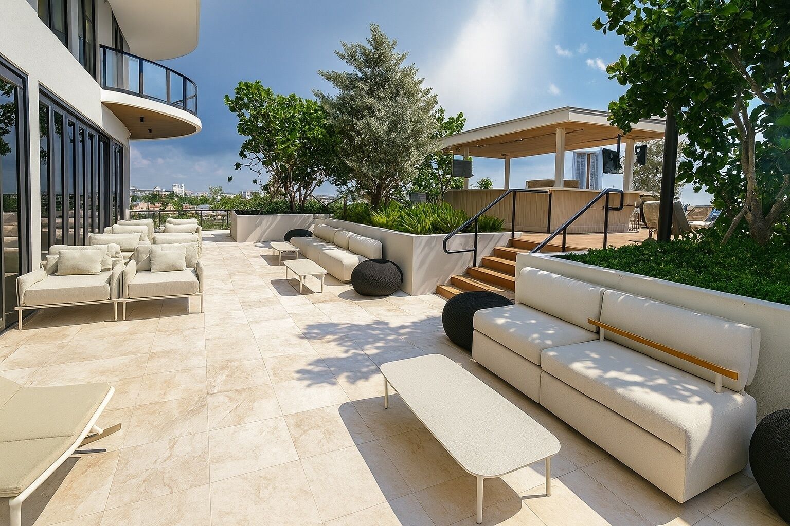 Un'area relax esterna moderna con diverse opzioni di seduta, tra cui divani e poltrone, disposte attorno a un tavolino centrale.