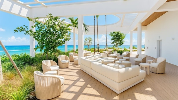 A sunlit outdoor lounge area with a large white sofa, multiple chairs, and a view of the ocean. - Luxury Beachside Oasis (Miami Beach)