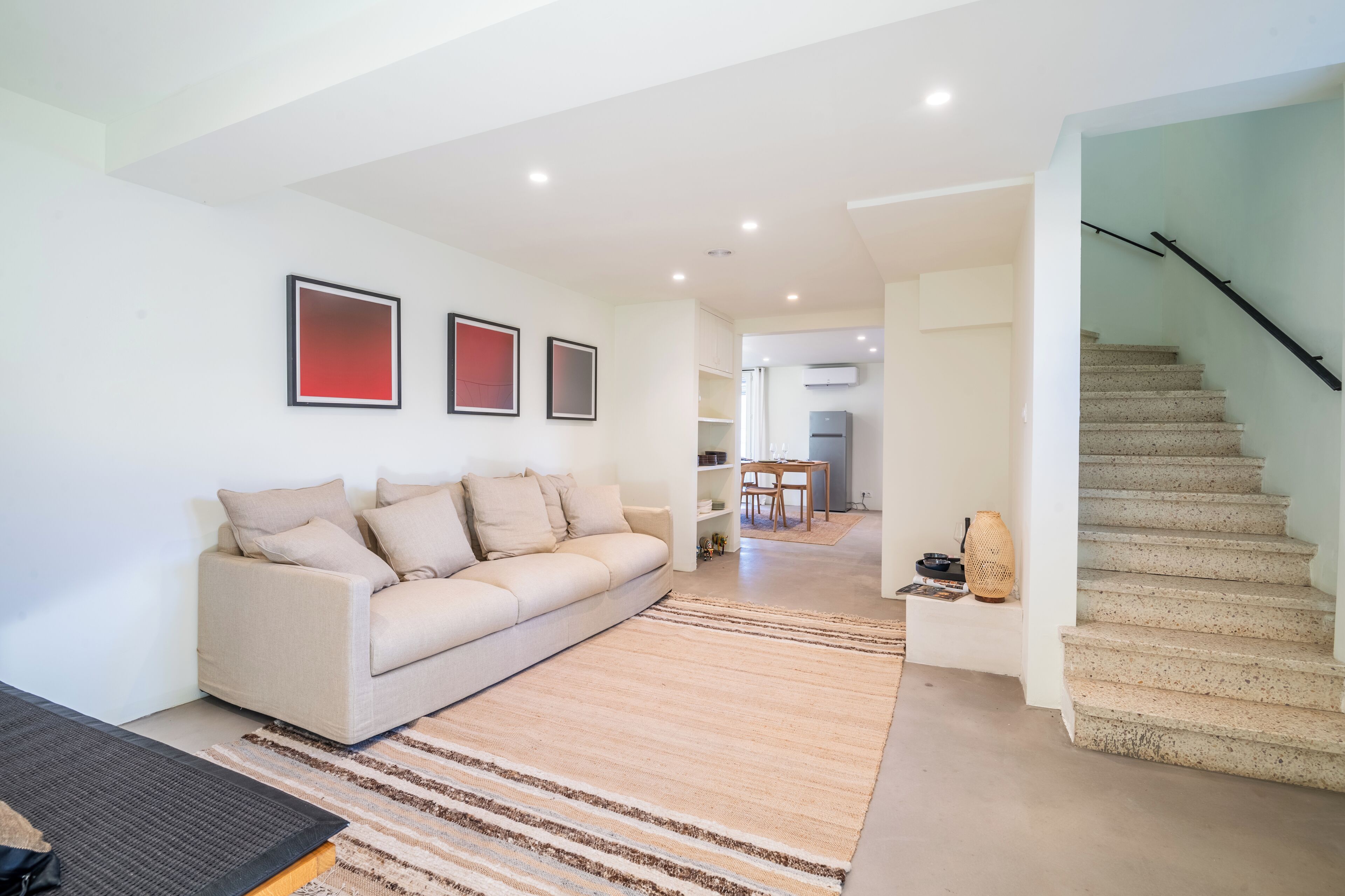 A modern living room with a beige sofa, a coffee table, and a staircase.