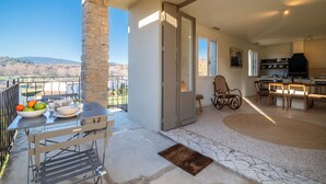 A spacious balcony with a stone pillar, a dining area with a table and chairs, and a kitchen with a stove and chairs.