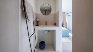 A bathroom with a sink, mirror, towel rack, and a blue container.