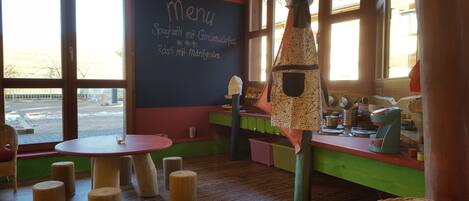Interior acogedor de un restaurante con un menú en pizarra, taburetes de madera y vistas a la calle.