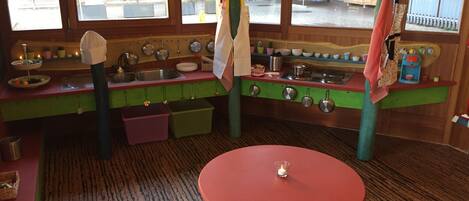 Une cuisine avec des meubles de rangement en bois, une table rouge et une fenêtre donnant sur l’extérieur.
