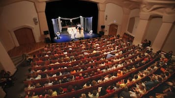 Un auditorio con hileras de asientos rojos y un escenario al frente.