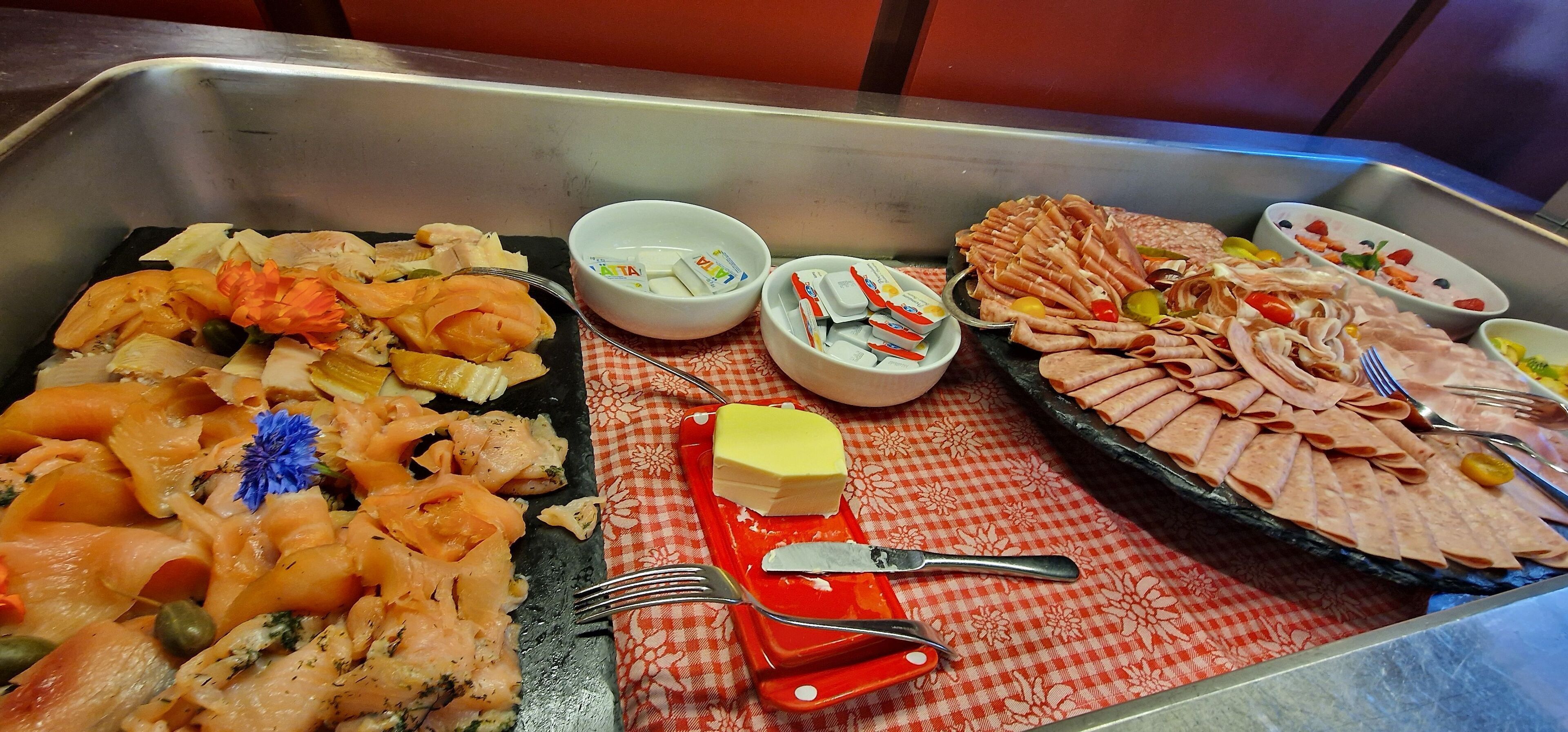 A buffet with various dishes including salmon, cheese, and meats.