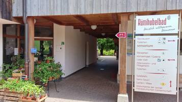 Une entrée en bois, avec une enseigne indiquant la présence de différents services, notamment un restaurant, des toilettes et un espace d’accueil.
