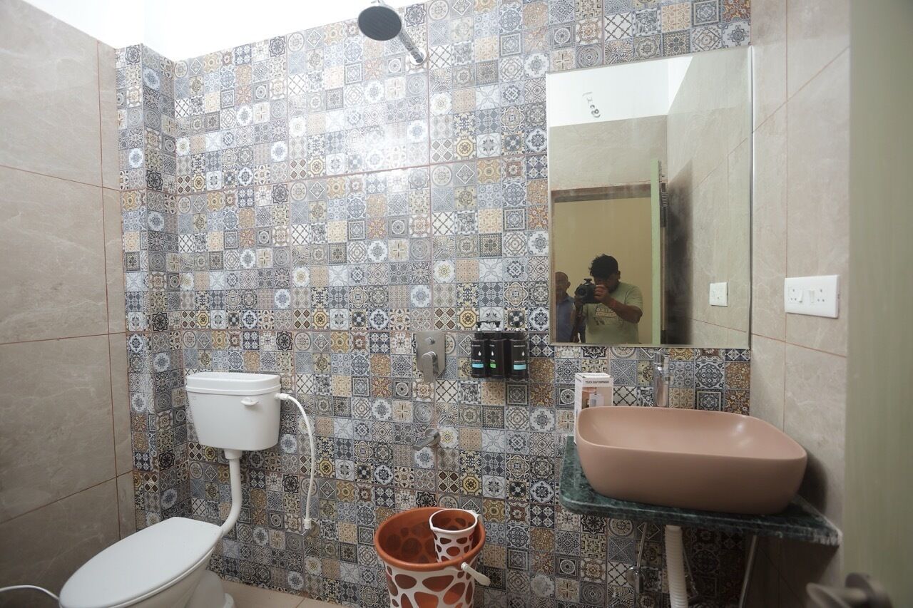 Ein Badezimmer mit einer Wand aus gemusterten Fliesen, einer Toilette, einem Waschbecken und einem Spiegel.