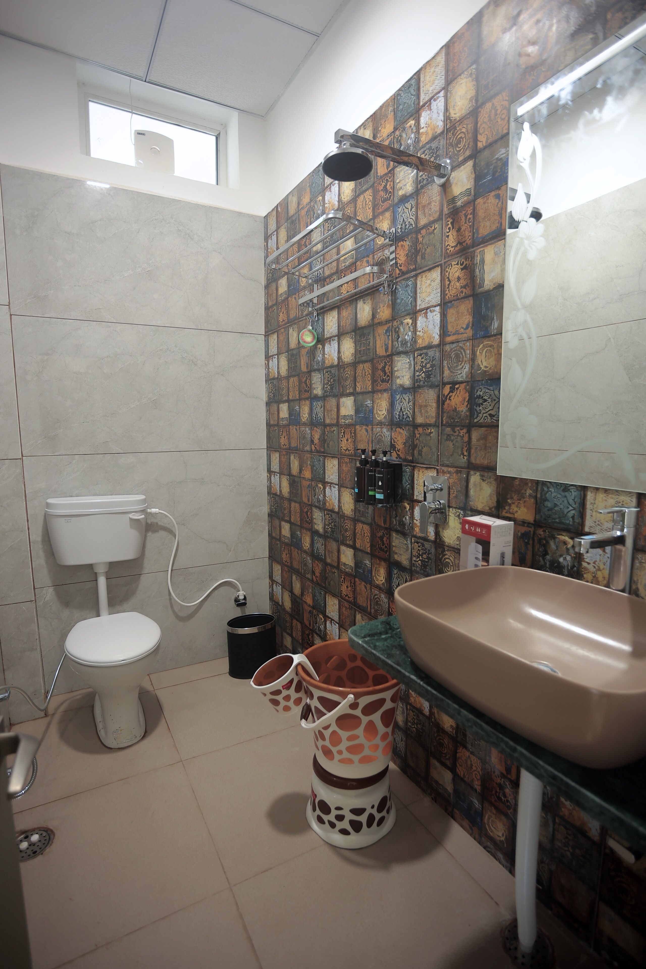 Un baño con inodoro, lavamanos, ducha y pared de azulejos.