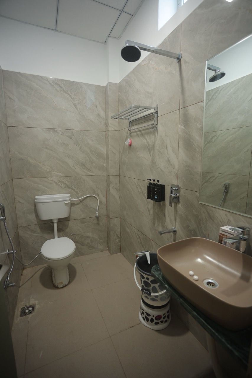 A bathroom with a toilet, shower, sink, and a mirror.
