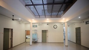 Un vaste hall d’entrée avec un plafond haut, des spots encastrés et une horloge au mur.