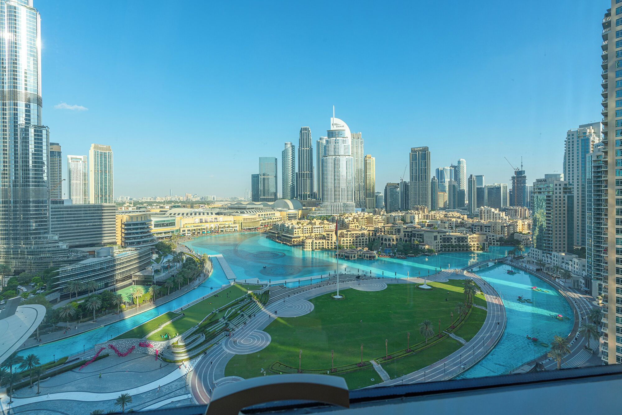 A cityscape with a large, modern building and a central plaza with a circular water feature.