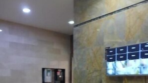 A reception area with a marble counter, a wall-mounted TV, and a small shelf with a water dispenser.