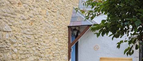 Um edifício de pedra com um banco de madeira na parte externa.
