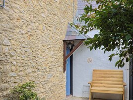 Un edificio de piedra con un banco de madera afuera.