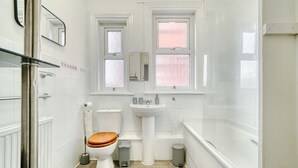 A modern bathroom with a toilet, sink, and bathtub. - Chester Road Cozy House in Manchester (Manchester)