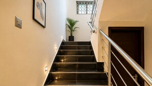 Un escalier avec une rampe, un pot de fleurs et une porte en bas.