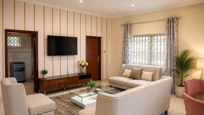 Un salon moderne avec un canapé, des fauteuils, une table basse et un téléviseur fixé au mur.