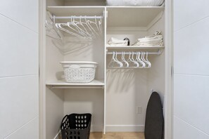 Closet with hangers, iron and ironing board, plus a laundry basket