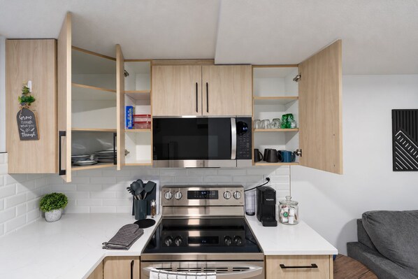 A modern kitchen with wooden cabinets, a stainless steel stove, and a microwave.