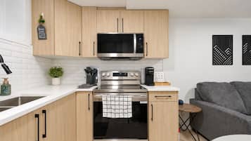 Una cucina moderna con mobili in legno, forno in acciaio inox, microonde e macchina da caffè.