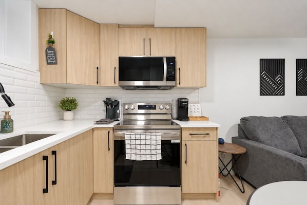 Una cocina moderna con armarios de madera, un horno de acero inoxidable, un microondas y una cafetera.