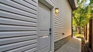 A house with a white exterior, a front door, and a small porch area. - Modern Suite 2 by Royal Alex Hospital, LRT, Rogers| Free WiFi, Parking & Netflix (Edmonton)