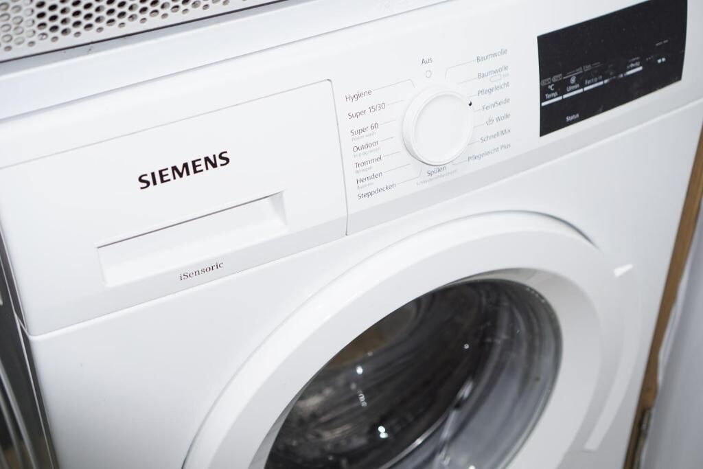 Une machine à laver Siemens blanche, dotée d’un panneau de commande et d’un écran numérique.
